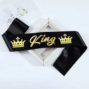 Detail of black satin party sash with gold foil King text and crown icons