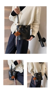 Detail of minimalist black leather bucket bag with gold lettering and plush dog pendant