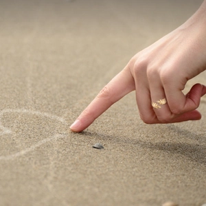 Minimalist golden leaf wrap ring with adjustable open band for women in a beach setting