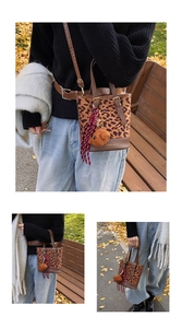 Detail of leopard print bucket bag with woven rope charm and plush ball on park bench