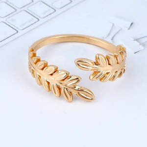 Minimalist gold leaf open ring with adjustable laurel branch design on a white desk