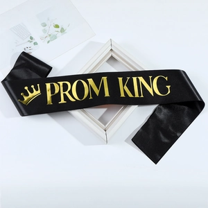 Close-up of black satin PROM KING sash with shiny gold foil lettering and crown