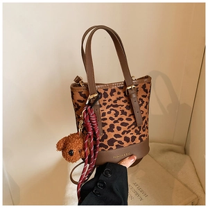 Close-up of leopard print tote bag with brown leather base and cute plush bear charm