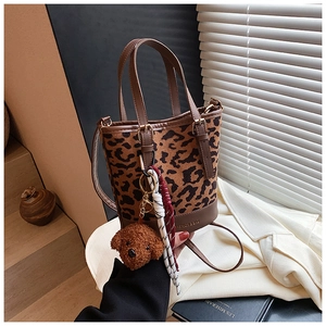 Detail of leopard print bucket bag with brown leather base and plush dog charm