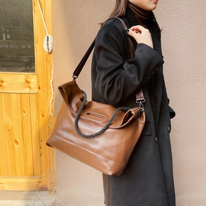 Brown faux leather tote bag with woven handles shown on a model for a commute look