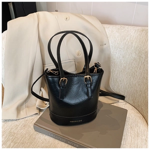 Close-up of black retro bucket bag with gold hardware and logo on a stylish office setting