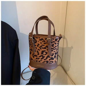 Close-up of leopard print bucket bag with brown PU leather trim and metal hardware detail
