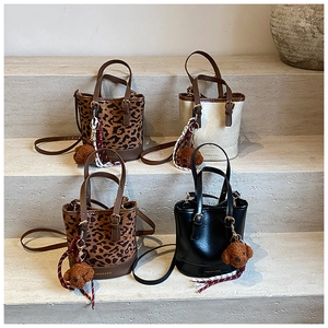 Group of leopard print and solid bucket bags with plush bear charms on stone steps