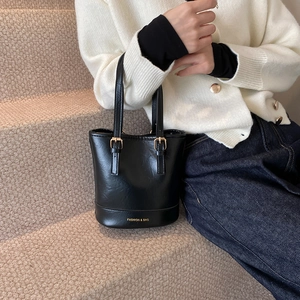 Glossy black patent leather bucket bag with gold hardware and shoulder straps