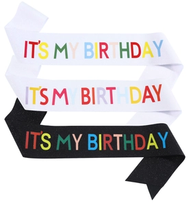 Close-up of glitter fabric sashes with rainbow IT'S MY BIRTHDAY text on black and white