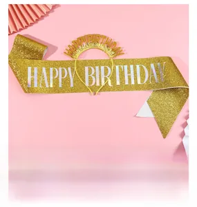 Close-up of golden glitter Happy Birthday sash and matching headband on a pink backdrop