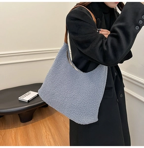 Detail of blue faux shearling hobo bag with brown leather strap on model in black coat