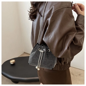 Detail der schwarzen Strass-Eimertasche mit weißen Perlenanhängern und Silberkettenriemen