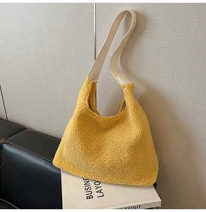 Detail of soft yellow faux fur tote bag with smooth beige shoulder strap on a white stand