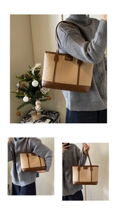 Detail of woven beige tote bag with brown leather base and fashion metal logo plaque