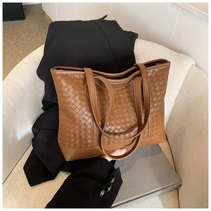 Detailed view of brown woven checkerboard tote bag on chair with business attire