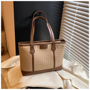 Detail of woven fiber texture and brown leather trim on a vintage style tote bag