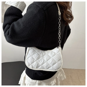 Detailed side view of white quilted shoulder bag with silver chain strap on model