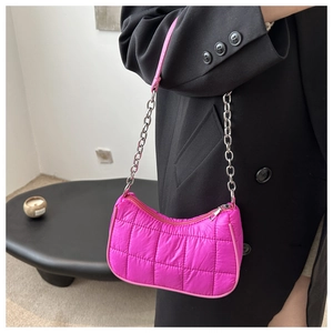 Gros plan du sac baguette matelassé fuchsia avec chaîne argentée sur un blazer noir