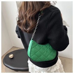 Detail of bright green quilted crescent shoulder bag with silver chain strap on model