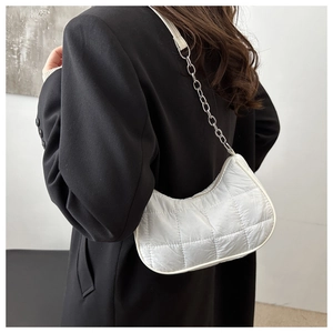 Vue de côté du sac demi-lune blanc matelassé sur un mannequin en blazer noir