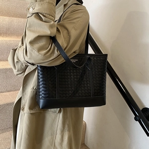 Vintage black woven tote bag with large capacity for women shown on a model's shoulder