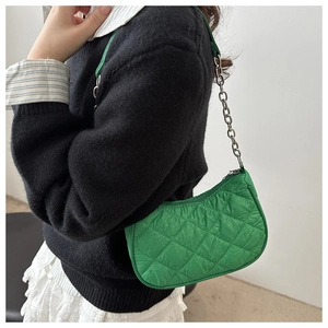 Detail of bright green quilted nylon texture and silver chain strap on underarm bag