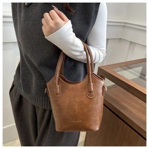 Close-up of brown bucket bag with embossed Fashion & Bags text and premium leather texture