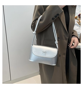 Close-up of silver crossbody bag featuring a bow detail and knotted shoulder strap