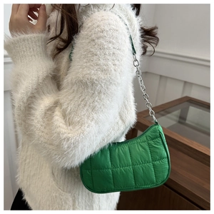 Détail d'un sac à bandoulière matelassé vert vif avec chaîne argentée porté par un mannequin