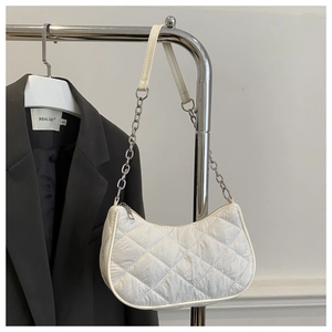 Detailed view of white quilted rhombic texture and silver chain strap on the handbag