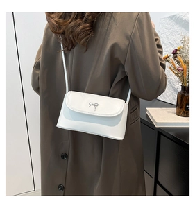 Detailed shot of white leather crossbody bag with silver bow buckle on model