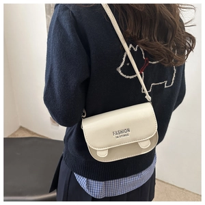 Détail d'un sac besace blanc crème montrant le logo argenté et la texture lisse en PU