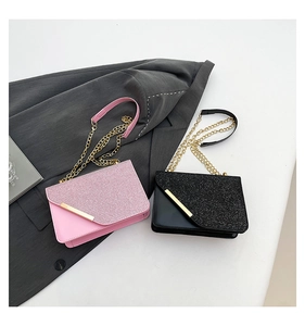Detail of pink and black crossbody bags featuring glitter flap and gold chain straps