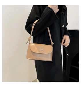 Detail of khaki crossbody bag with silver bow hardware and knotted shoulder strap