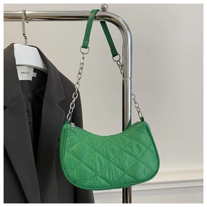 Detail of green quilted puffer shoulder bag featuring silver chain strap and zip closure