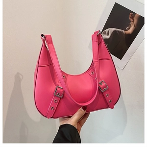 Detail der rosa Halbmondtasche mit Punk-Metallösen und dekorativen Schnallenriemen