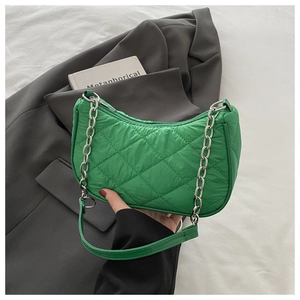 Close-up of green quilted nylon handbag with silver chain strap and leather handle