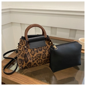 Detail of leopard print tote set with brown resin handle and black clutch on a table