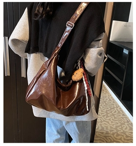 Deep brown glossy patent leather hobo bag with adjustable strap and bear pendant