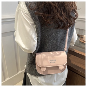 Détail d'un sac besace rose en similicuir porté avec une tenue de bureau décontractée