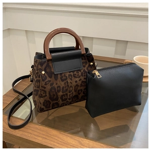 Detail of leopard print suede tote with a matching black zipper pouch on a wooden table