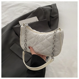 Detail of white quilted rhombus pattern on a chic crossbody bag with silver chain