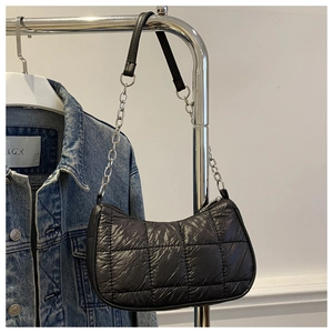 Detail of black quilted nylon puffer bag featuring silver chain strap and square texture