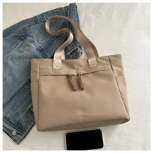 Detail view of khaki nylon tote bag with drawstring straps and side pocket