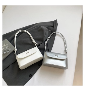 Detailed view of small square shoulder bags in white and silver with bow clasp