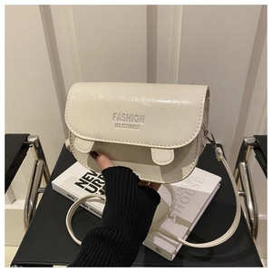 Gros plan détaillé du sac selle en similicuir crème avec inscription Fashion Instinct