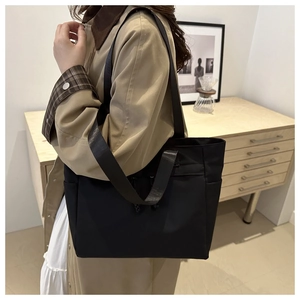 Detail of black nylon tote bag with dual straps shown in a stylish office commuter setting
