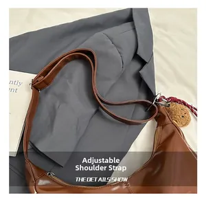 Detail of adjustable shoulder strap and brown plush bear charm on minimalist tote bag