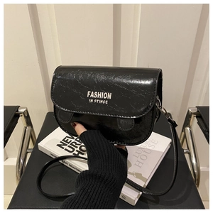 Détail du sac de selle noir brillant avec imprimé texte de mode et rabat à fermeture aimantée